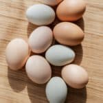 set of multicolored raw eggs on wooden table