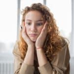 puzzled woman with pen studying in room