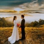 couple standing on grass field while looking at each other